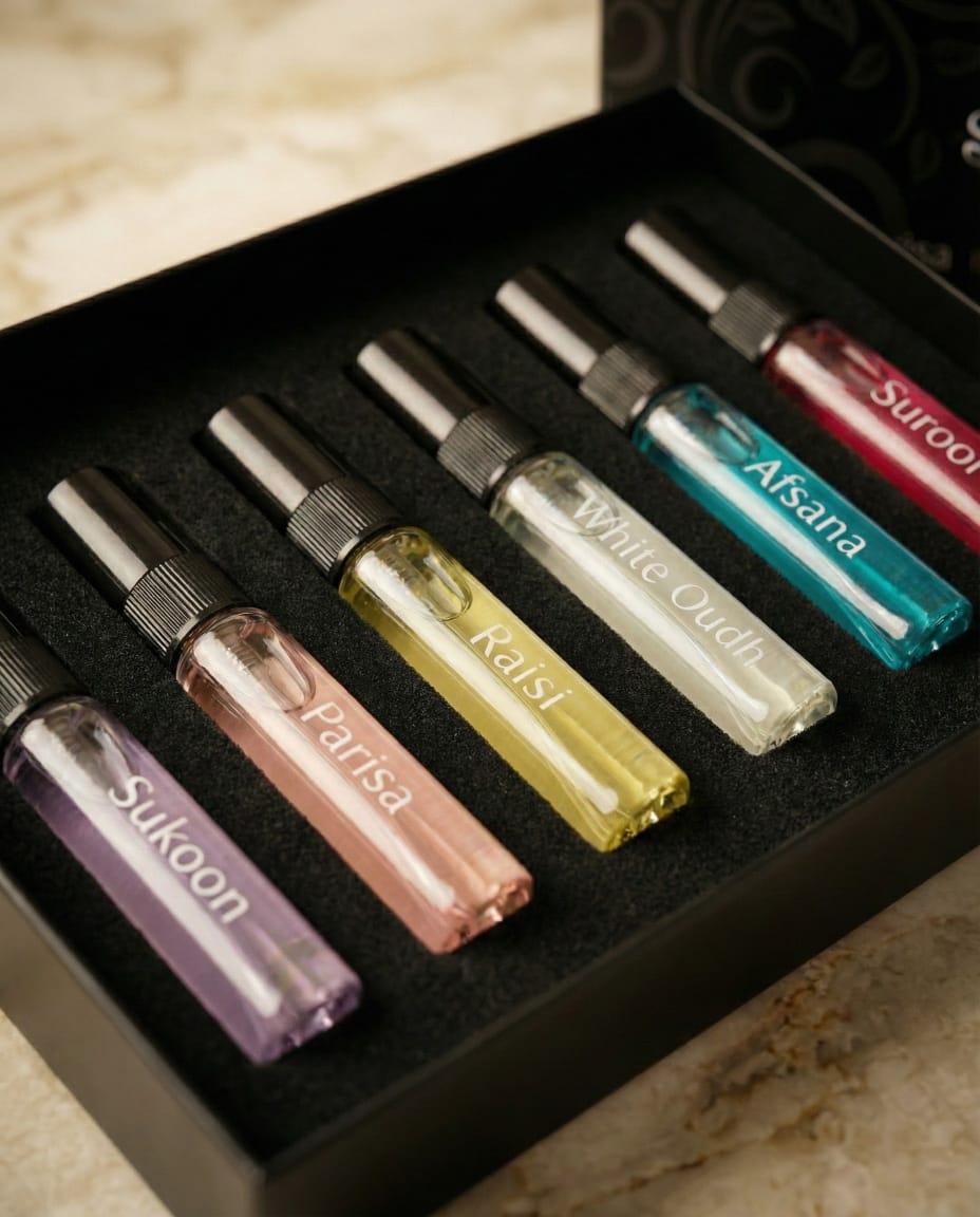 Set of small glass bottles with metal caps, each labeled with a different brand name, arranged in a black box.